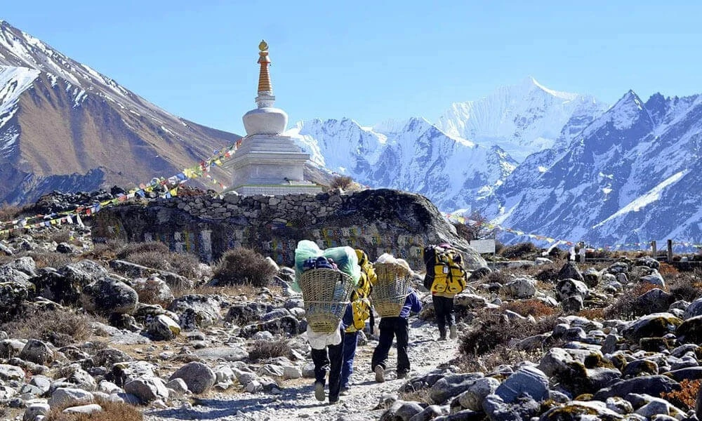 Beautiful view of helambu trail with guides carrying big bags and a buddha stup in the top
