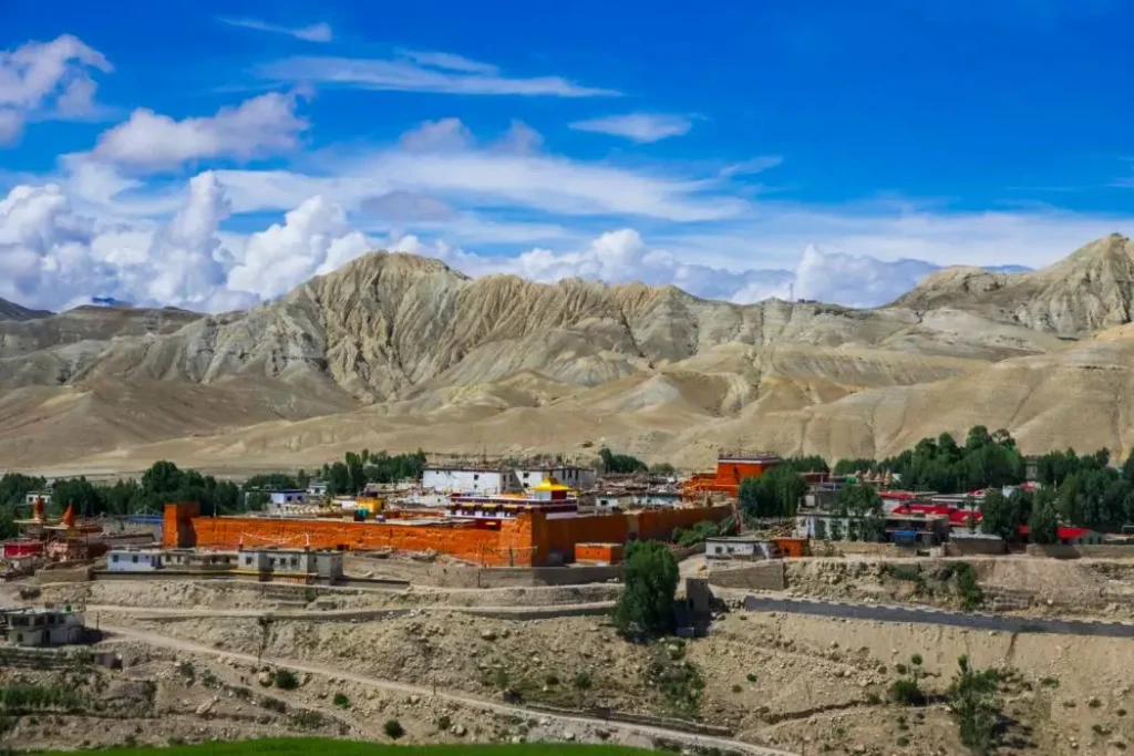 Elevated view of the historic walled city of Lo Manthang featuring ochre monastery walls set against desert mountain cliffs