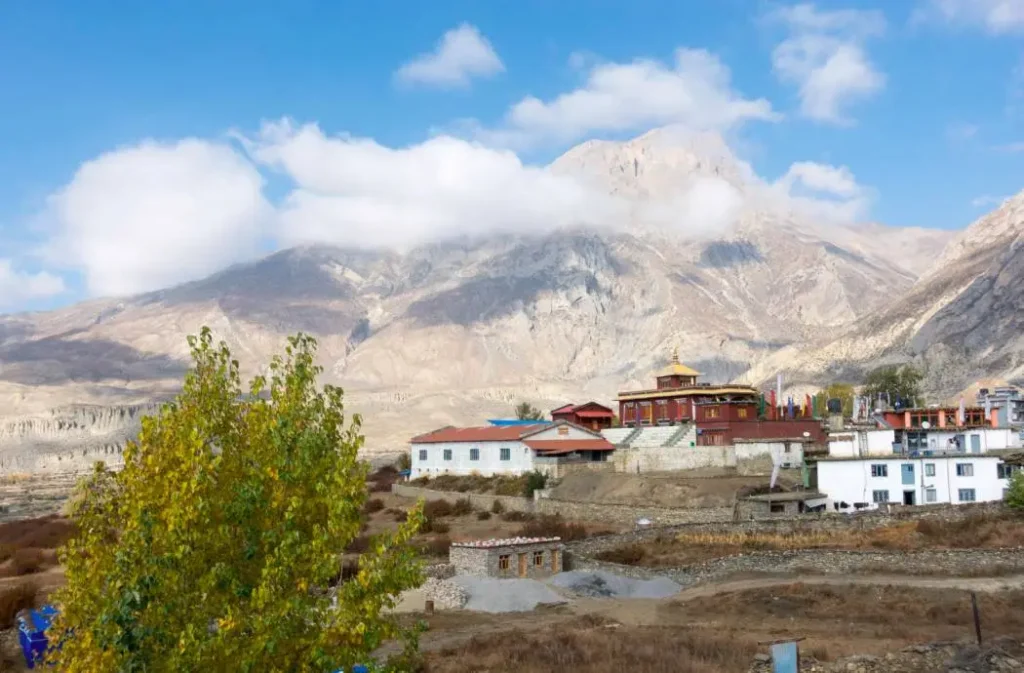 Close-up of Muktinath monastery with vibrant autumn trees and towering Himalayan mountains in the background