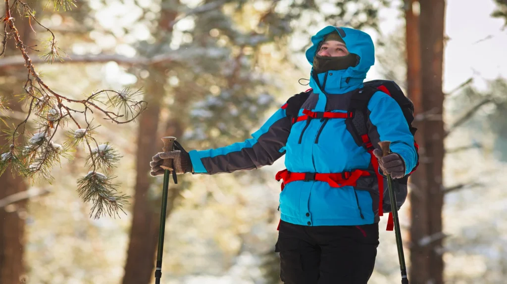 A trekker with thick clothing layering, a backpack and with trekking stick